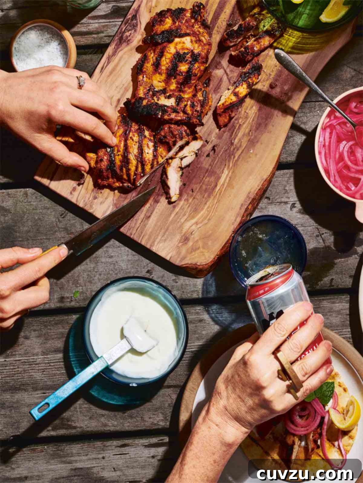 Zesty Charred Boneless Chicken Thighs 3 A person carving spiced grilled boneless chicken thighs on a wooden platter.
