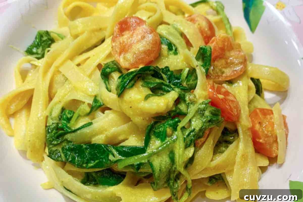 Vibrant Turmeric Shrimp Linguine 5 A white plate filled with turmeric shrimp linguine and wilted arugula