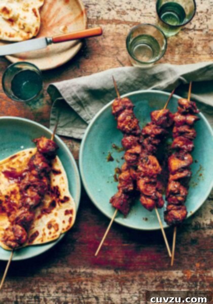 Three easy marinated chicken skewers on a blue plate and a fourth one on top of a piece of flatbread, garnished with fresh herbs.