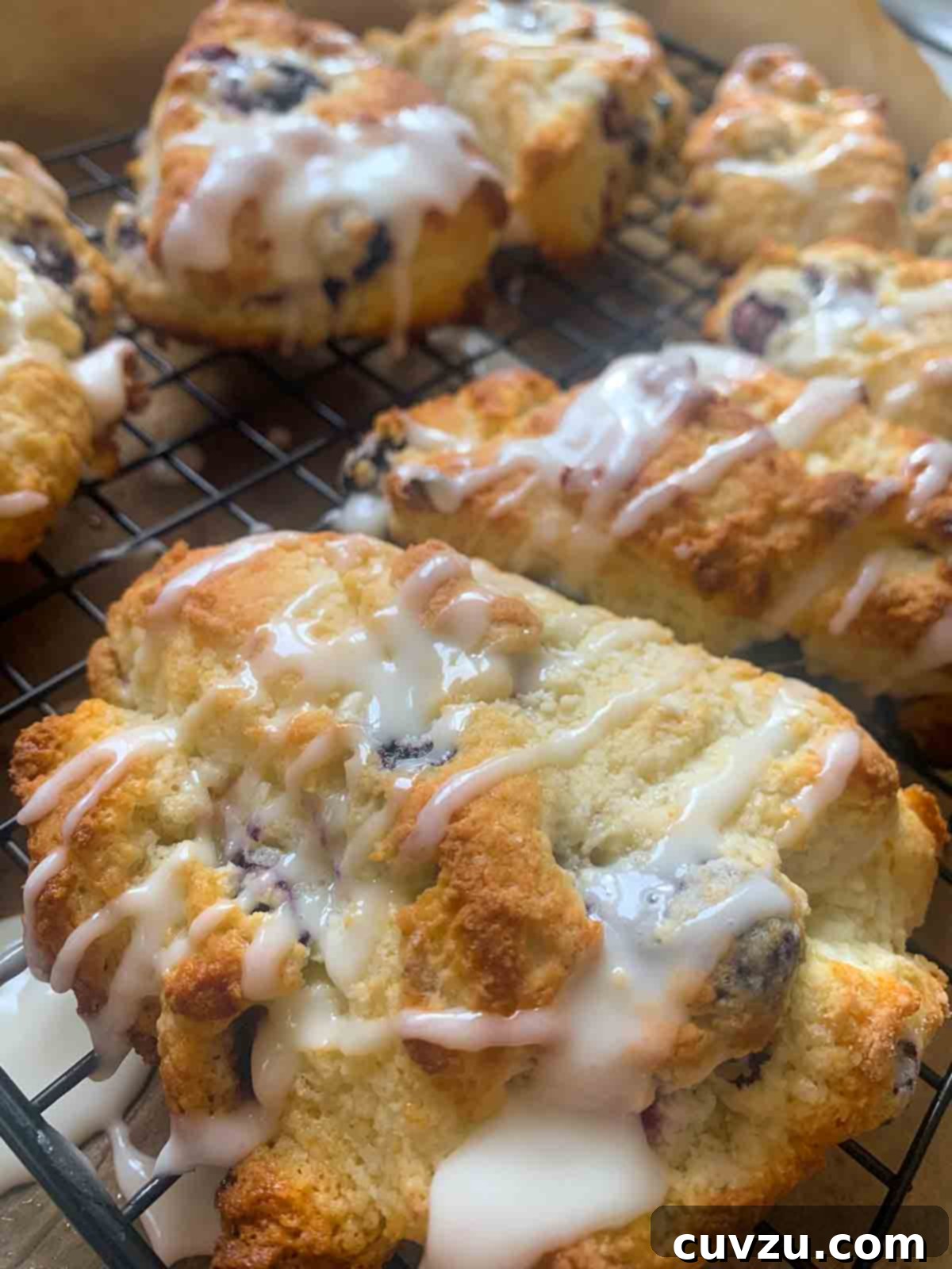 Zesty Lemon Blueberry Scones 7 Glazed blueberry lemon scones cooling on a wire rack.