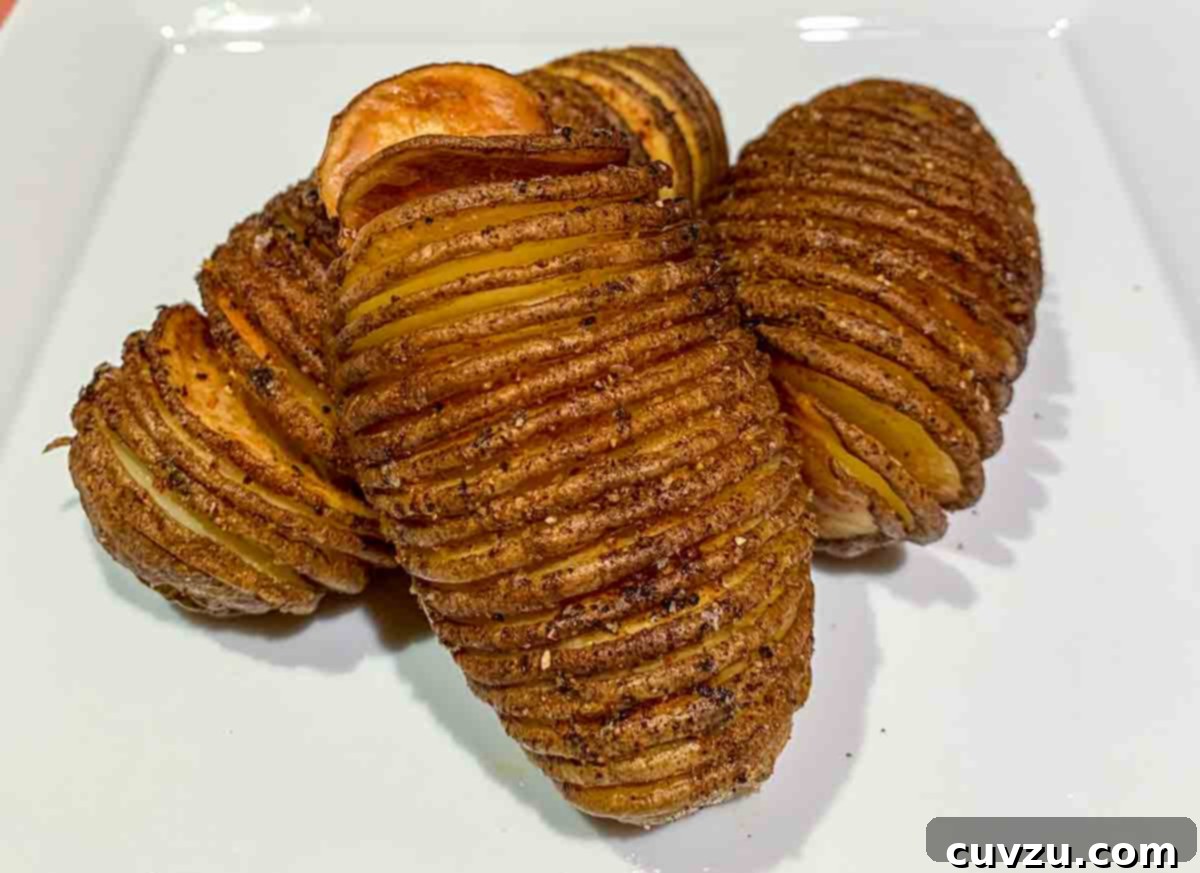 Crispy Air-Fried Hasselback Potatoes 7 Three air fryer hasselback potatoes piled on a white square plate.