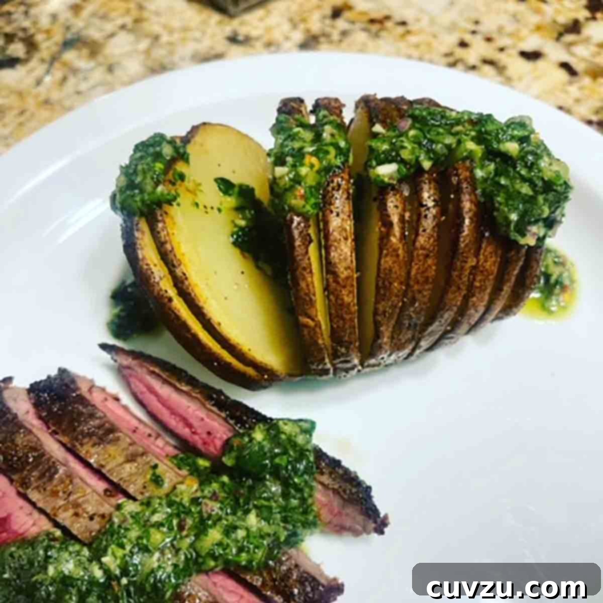 Crispy Air-Fried Hasselback Potatoes 6 An air fryer hasselback potato and a sliced steak with herb sauce on top on a white plate.