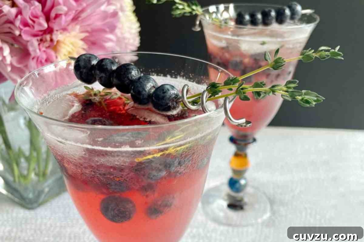Blueberry Bliss Spritz 5 Two glasses of blueberry prosecco spritz with a skewer of blueberries and a sprig of thyme on top.