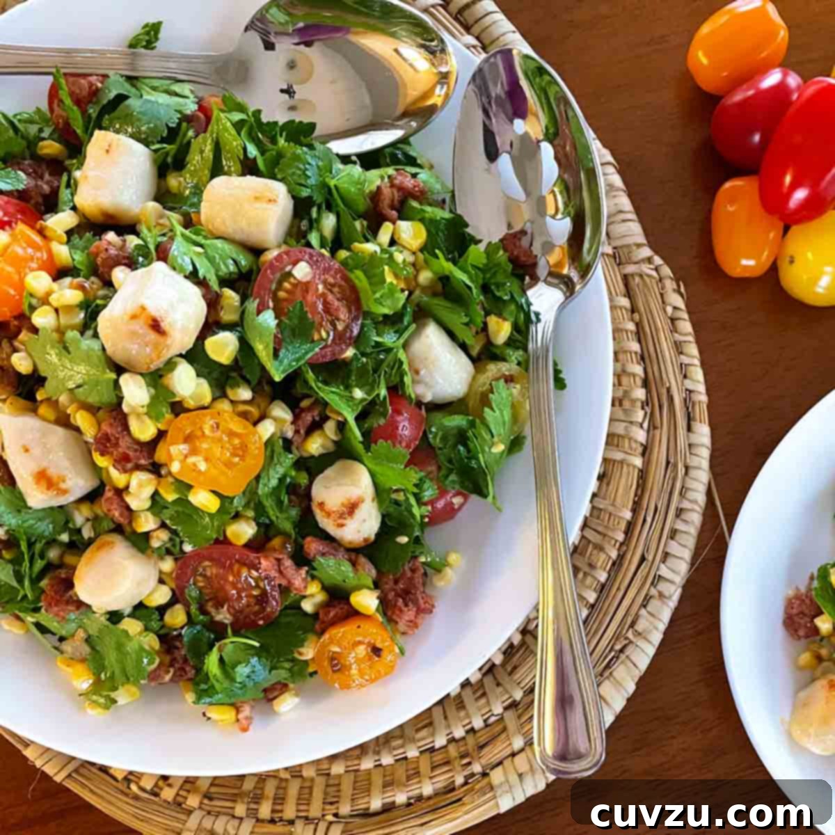 Seared Scallop Smoky Corn Salad with Zesty Lime 6 A white bowl filled with charred corn and scallop salad, with two spoons resting on the side.