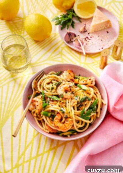 A vibrant pink bowl brimming with lemon garlic shrimp pasta, a fork resting invitingly within the spirals of pasta.