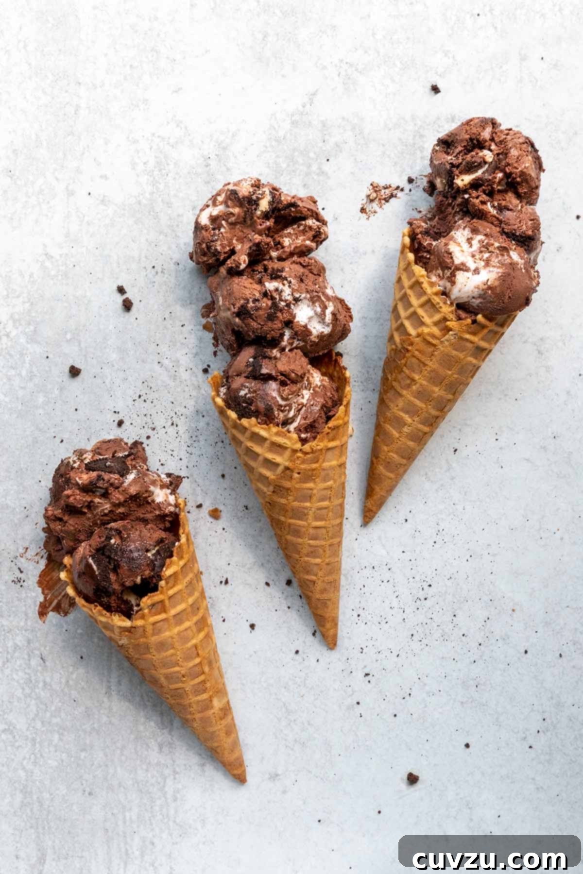 Velvety No-Churn Chocolate Oreo Marshmallow Swirl 2 Three waffle cones, each filled with two or three scoops of rich chocolate Oreo ice cream, glistening with marshmallow swirls.