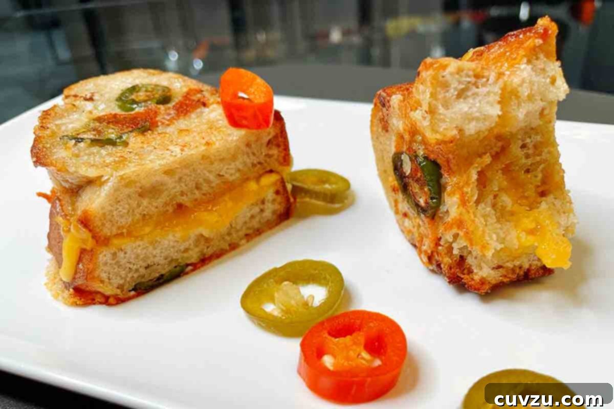 Crispy Parmesan Jalapeño Grilled Cheese 5 A halved Parmesan-crusted grilled cheese with jalapeños in the sandwich and on the plate beside it.