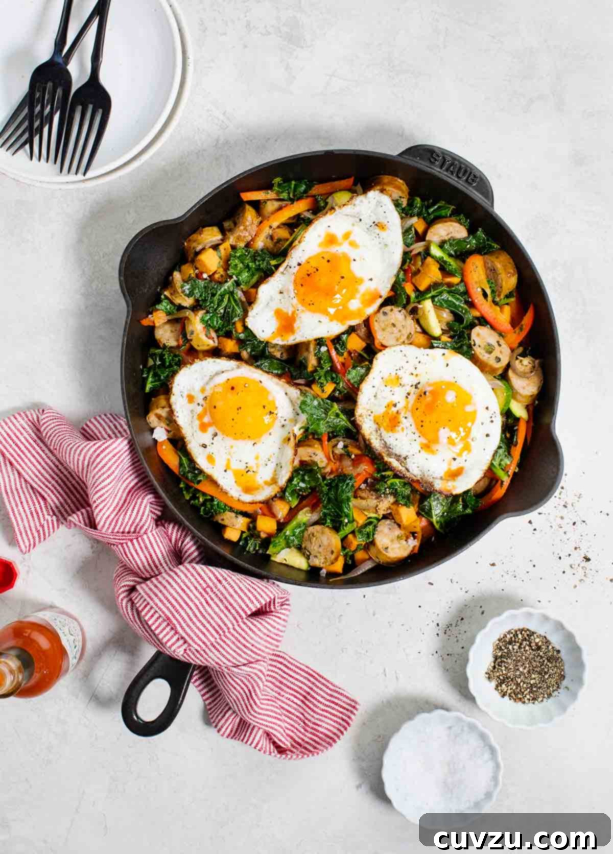 Hearty Sweet Potato Chicken Sausage Skillet 2 A cast-iron skillet filled with sweet potato and chicken sausage hash, topped with three fried eggs and fresh herbs.