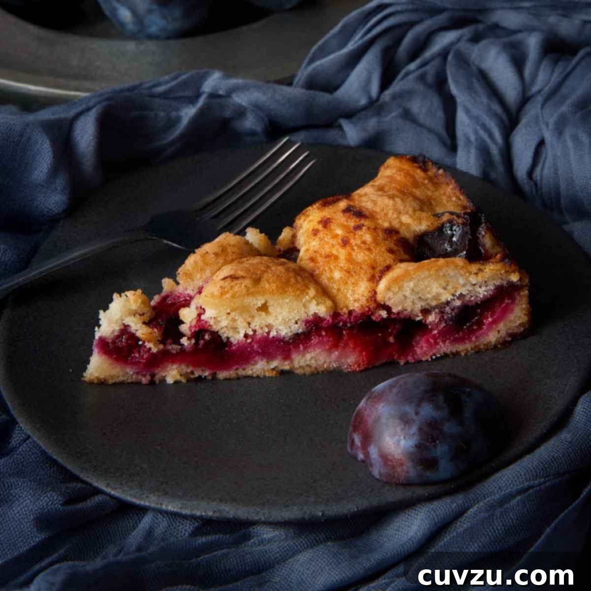 Close-up of a single slice of Marian Burros' plum torte, showing the jammy fruit filling.
