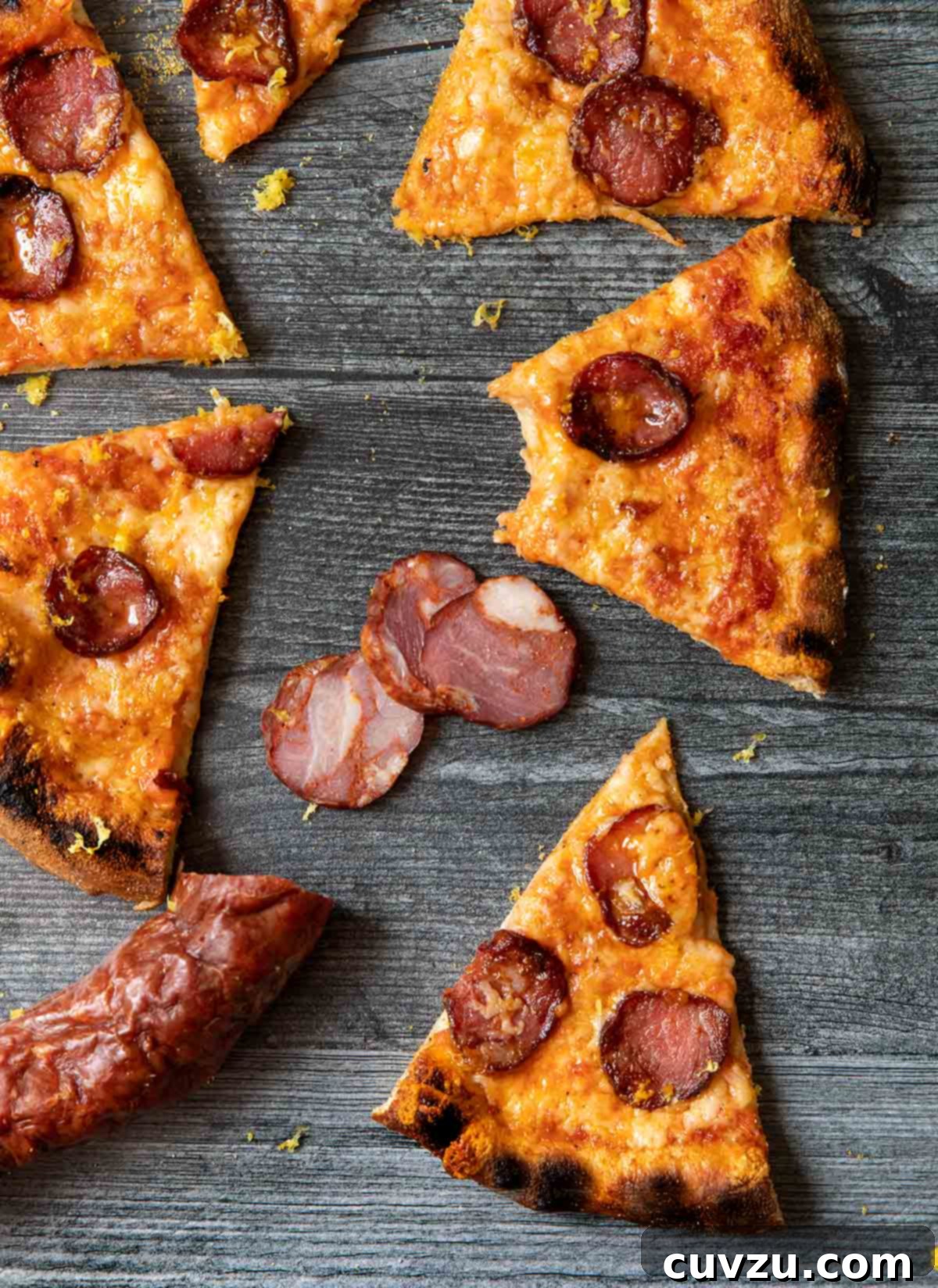 Sizzling Portuguese Sausage & Cheese Ooni Pizza 4 Sic slices An Ooni Portuguese pizza on gray weathered wood, with chouriço.