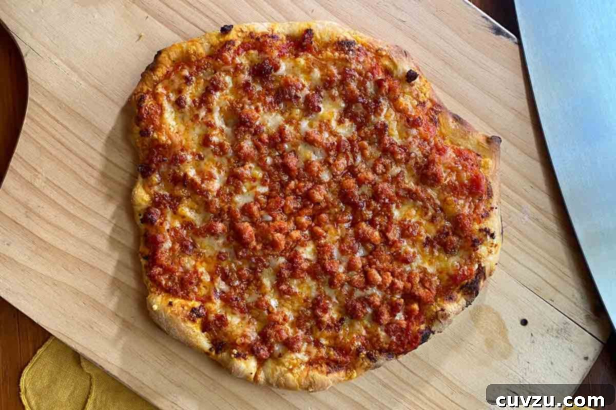 Sizzling Portuguese Sausage & Cheese Ooni Pizza 8 An Ooni pizza with Portuguese chourico and cheese on a cutting board.