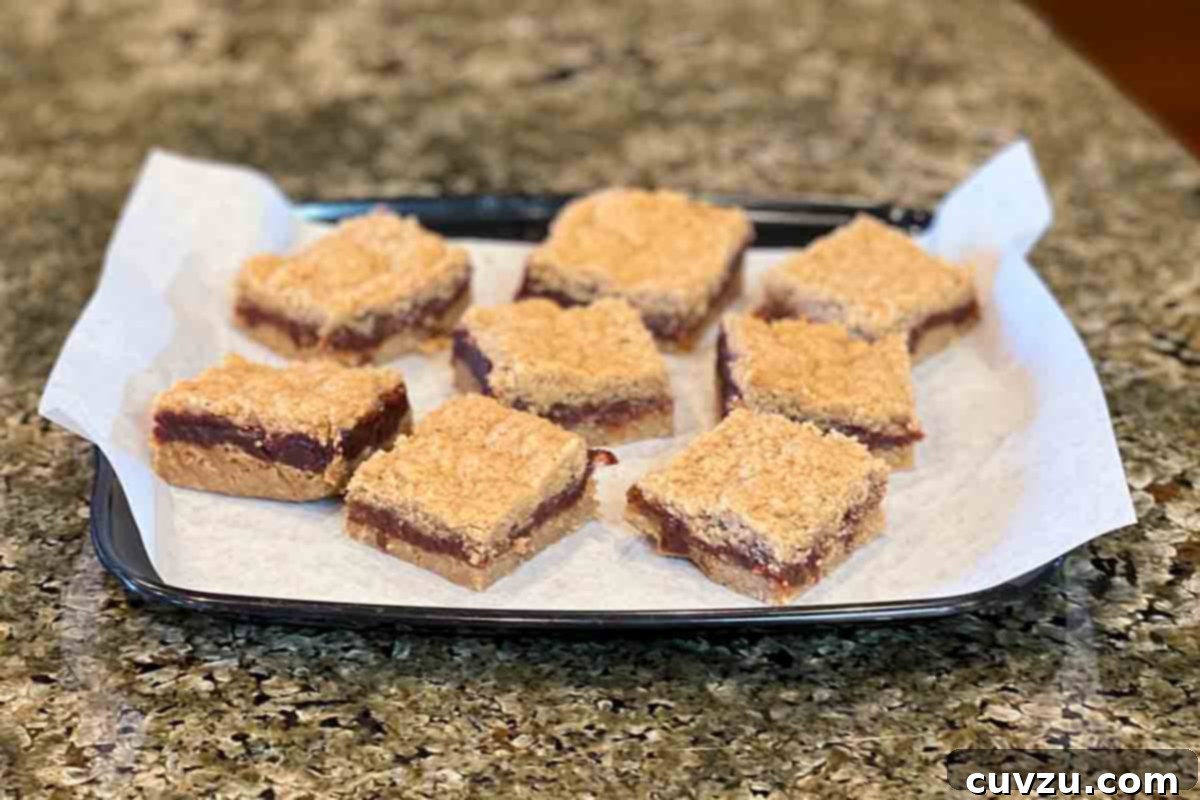 Golden Date Bars 5 Eight neatly cut date bars on a piece of parchment paper, showcasing the textured, golden-brown crust and the rich date filling, ready for serving.