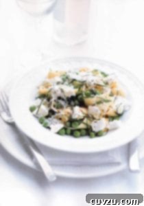A white bowl filled with lemon, ricotta, and pea pasta.