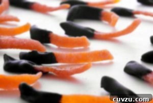 Strips of chocolate dipped candied orange peel on a white surface, exquisitely presented.
