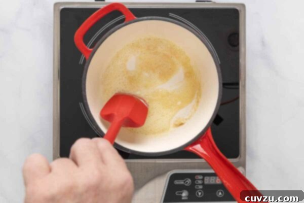 Golden Cheddar Drizzle 13 A person melting butter in a saucepan.