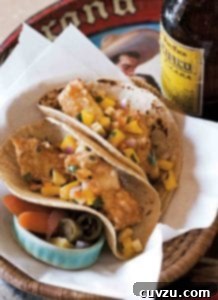 A basket containing two Baja-style tempura fish tacos and some pickled vegetables, with a bottle of Pacifico on the side.