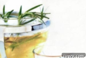 A pot of rosemary infused tea with rosemary sprigs sticking out the top and a glass beside it, inviting warmth and relaxation.