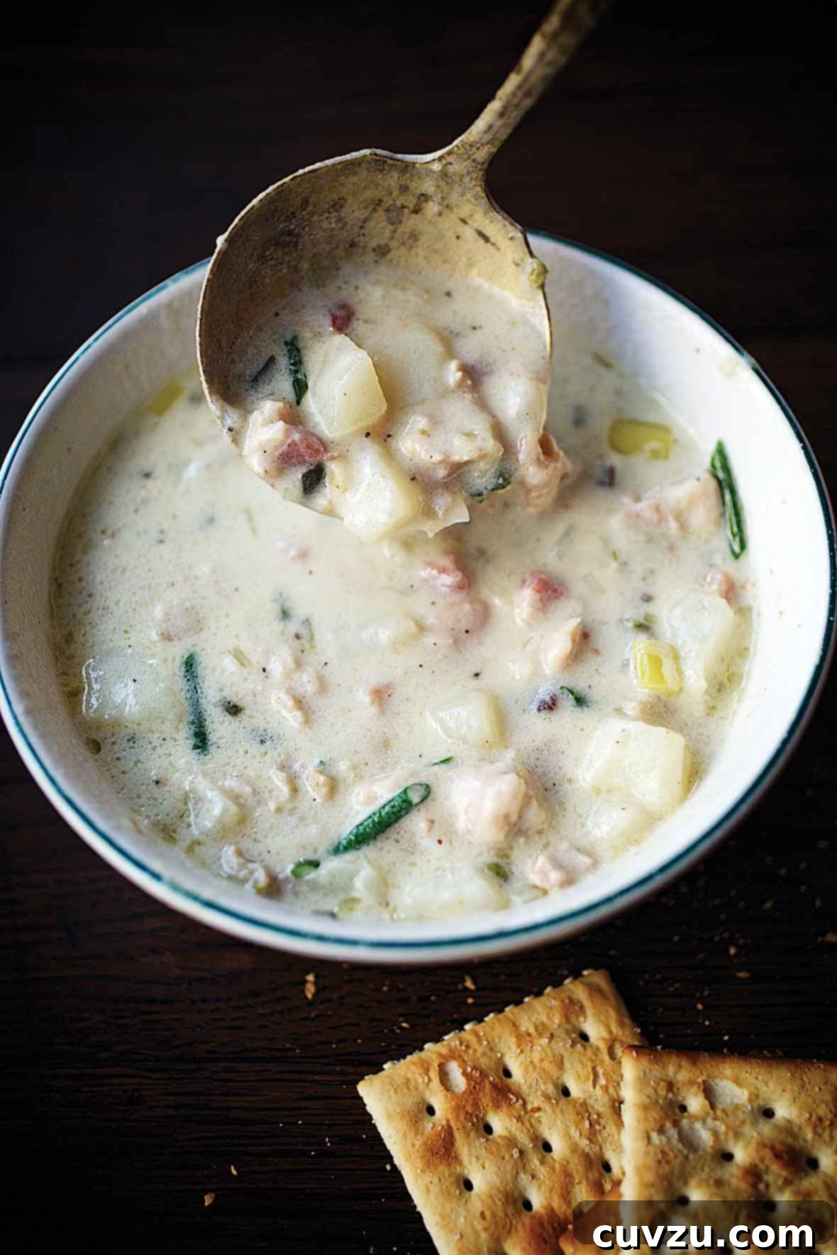 A bowl of creamy New England clam chowder with clams, potatoes, leeks, shallots, cream, and chives