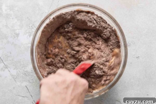 Irresistible Chocolate Muffins 15 A person mixing muffin batter in a glass bowl.