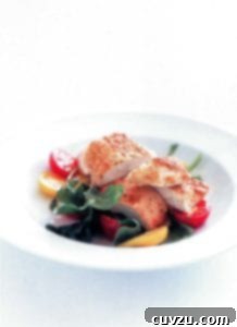 White bowl of sliced parmesan-crusted chicken, lettuce, and red and yellow cherry tomatoes