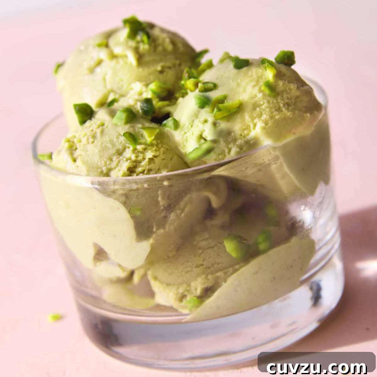 A bowl containing four scoops of pistachio gelato with chopped pistachios on top.