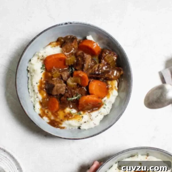 Hearty Slow Cooker Irish Beef Stew 4 Two bowls filled with mashed potatoes and topped with beef stew.