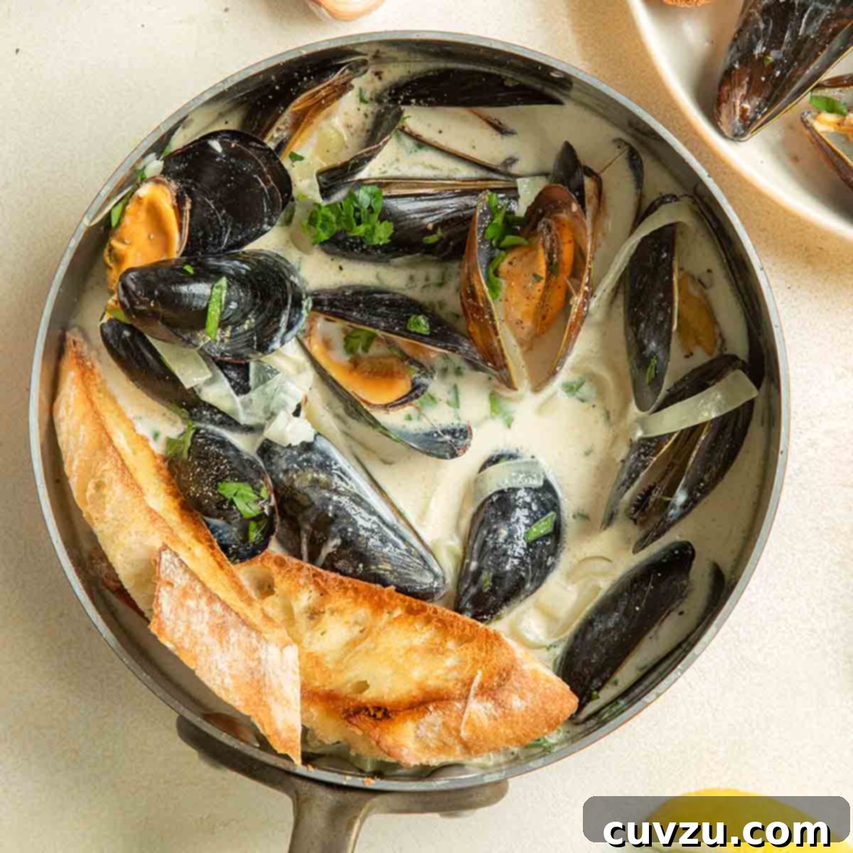 13 Recipes to Make Mom's Day Unforgettable 8 A copper saucepan filled with mussels in a creamy white wine garlic sauce with lemons.