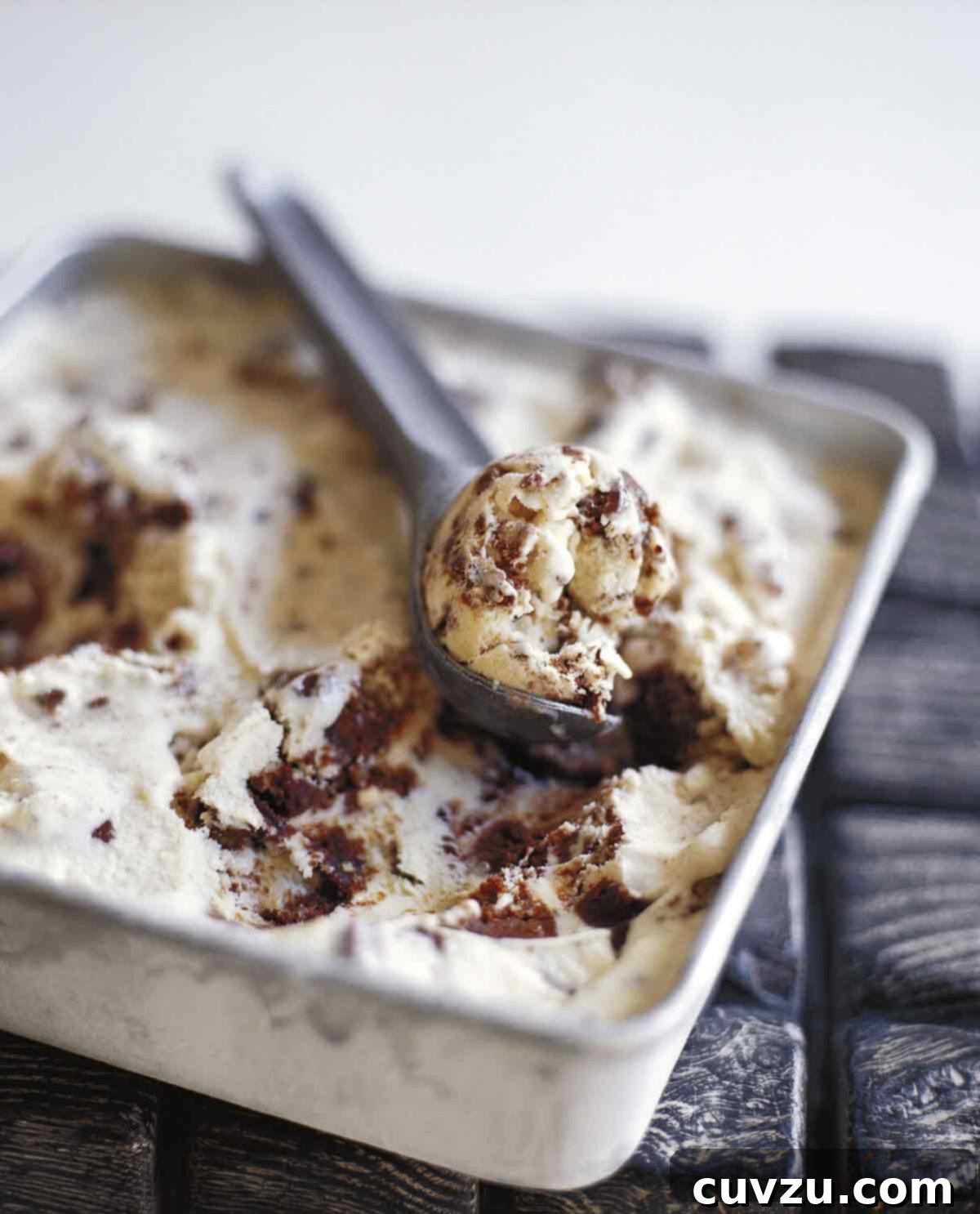 Sweet Six No-Churn Ice Cream Treats 7 A square metal dish filled with brownie ice cream and a metal ice cream scoop removing a scoop from the dish.
