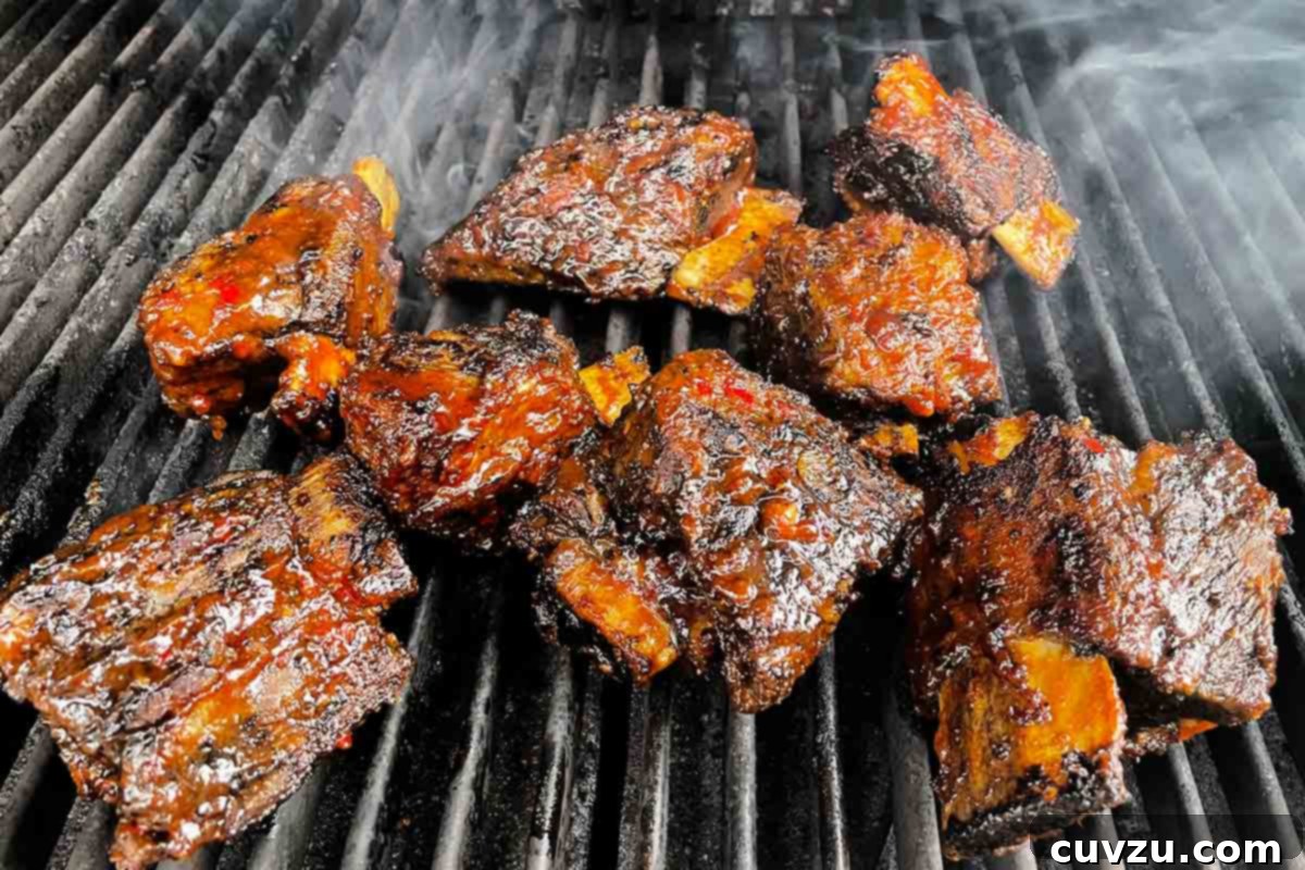 Smoky Bourbon-Glazed Short Ribs 12 Several grilled beef short ribs, coated with a thick layer of bourbon BBQ sauce, sizzling on a hot grill.