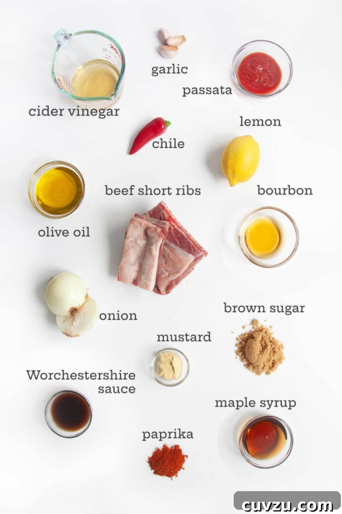 Smoky Bourbon-Glazed Short Ribs 4 A vibrant display of ingredients for grilled beef short ribs, including various spices, fresh onion, chile, garlic, passata, mustard, maple syrup, bourbon, and the star of the show: beef short ribs.