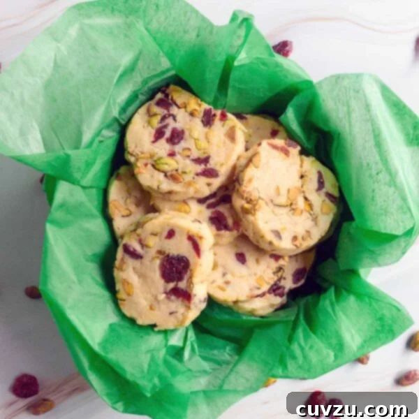 Cranberry pistachio cookies in a cookie tin lined with green tissue paper.