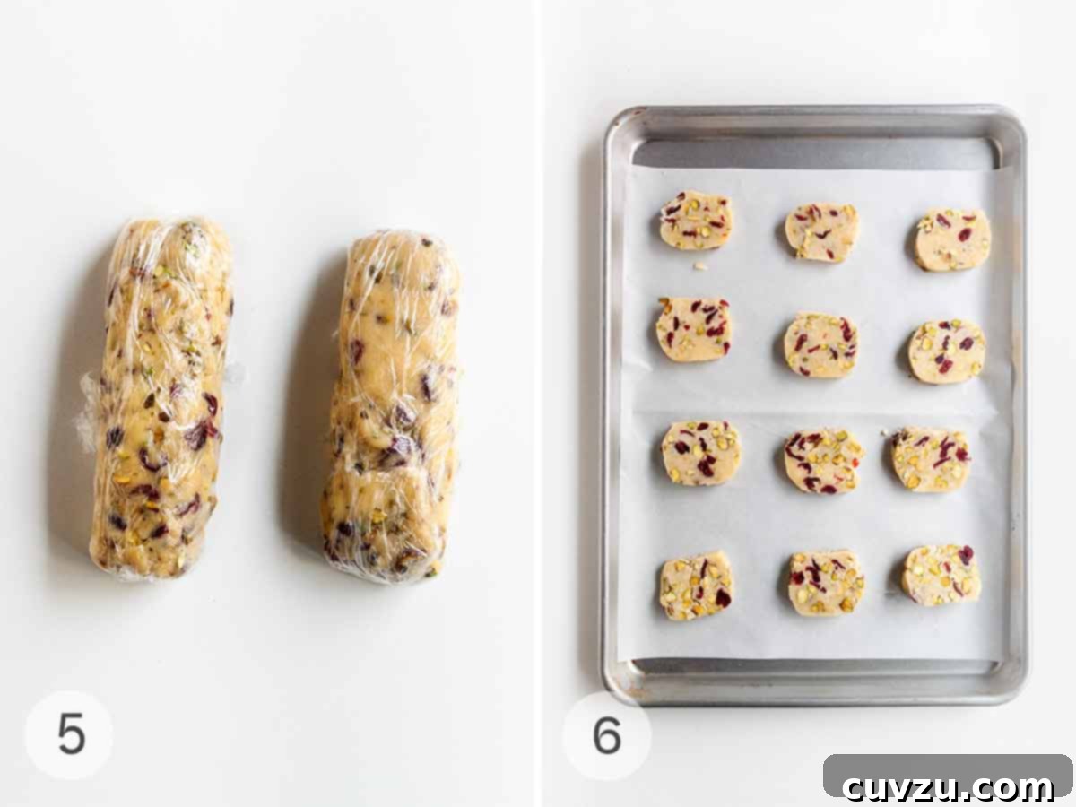 Jewel Toned Pistachio Cookies 7 The prepared cookie dough, neatly rolled into two uniform logs and tightly wrapped in plastic for chilling, alongside perfectly sliced cookie rounds arranged on a parchment-lined baking sheet, ready for the oven.
