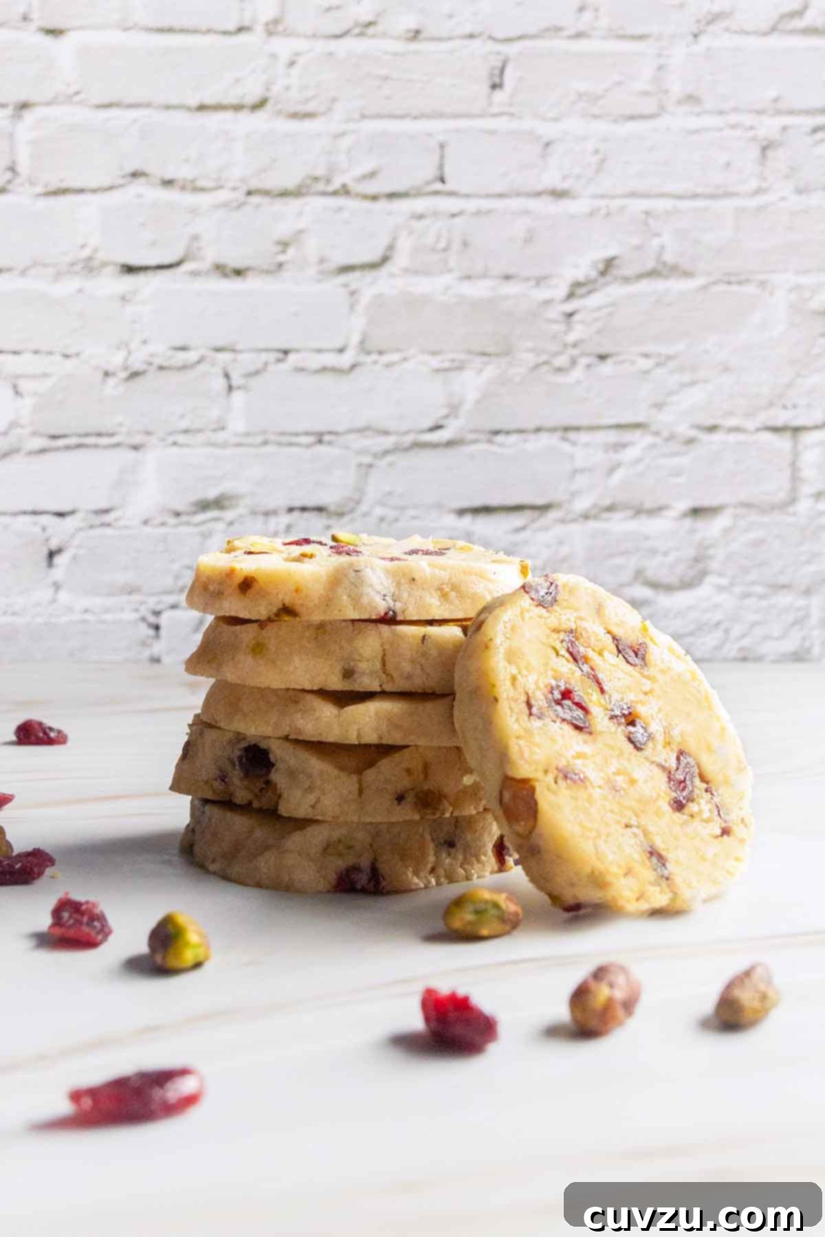 Jewel Toned Pistachio Cookies 9 A charming stack of five cranberry pistachio cookies, with another inviting cookie leaning casually against the base, showcasing their perfect round shape and festive colors.
