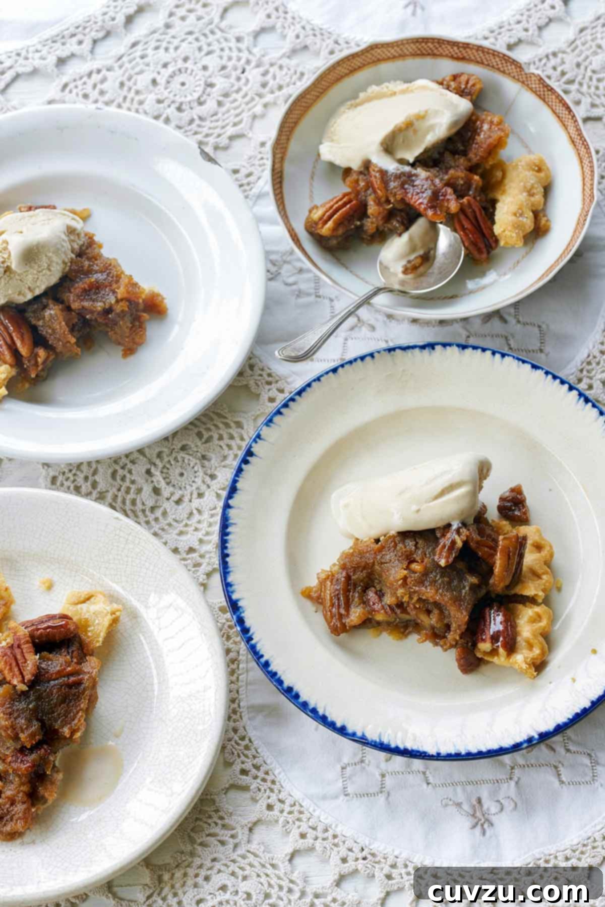 Four plates of rum pecan pie in a flaky crust, topped with whole pecans and vanilla ice cream.