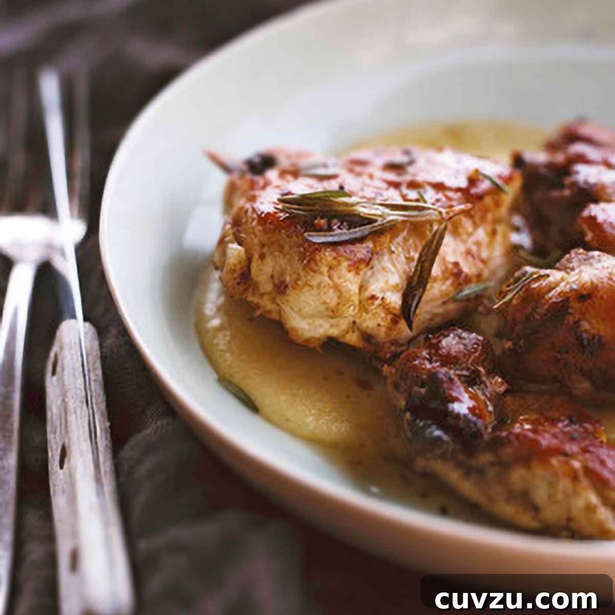 Six Flavorful Bone-In Chicken Breast Dinners 2 Chicken pieces in a sauce of vinegar, garlic, rosemary in a white plate, knife and fork on the side.