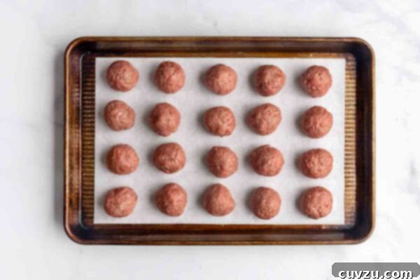 Velvety Meatball Stroganoff 12 Twenty golf ball-sized meatballs on a parchment-lined baking sheet.