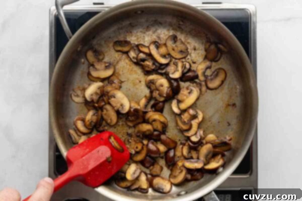 Velvety Meatball Stroganoff 13 A person sautéing mushrooms in a skillet.
