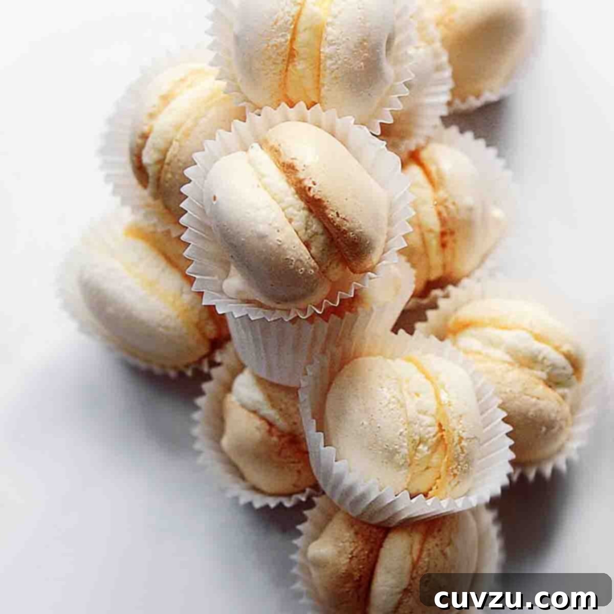 A pile of cream-filled macarons, each in a white wrapper.