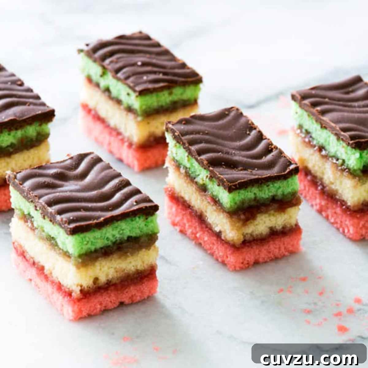 Six Italian rainbow cookies on a marble slab