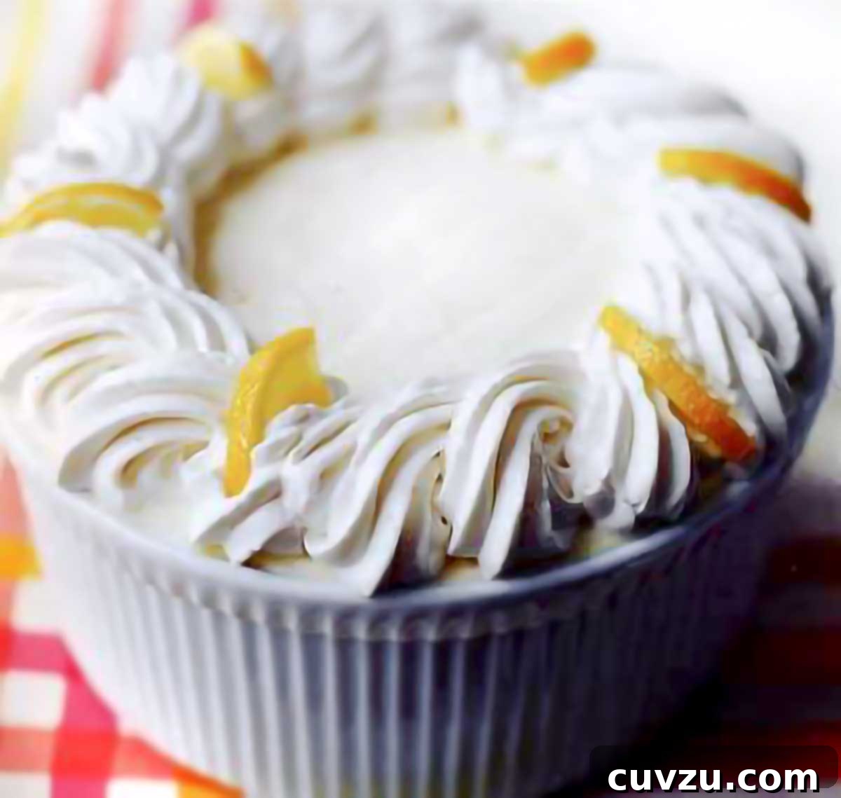 Barefoot Contessa fresh lemon mousse in a soufflé dish with the edges decorated with swirls of whipped cream and lemon slices.