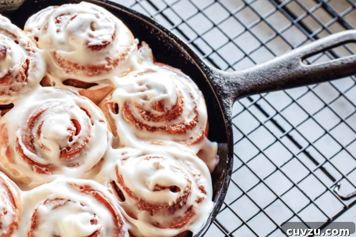 Gooey Biscuit Cinnamon Rolls 3 A cast-iron skillet filled with glazed biscuit cinnamon rolls on a wire rack.