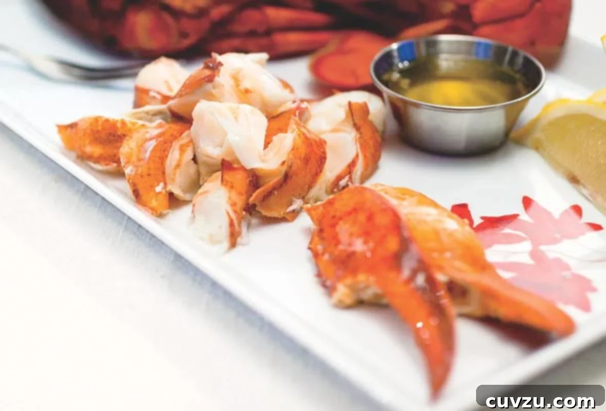 Buttery Lobster Bliss 2 A beautifully presented plate with perfectly steamed lobster, featuring its vibrant claws, chunky knuckles, and succulent tail meat, served alongside a small bowl of golden drawn butter.