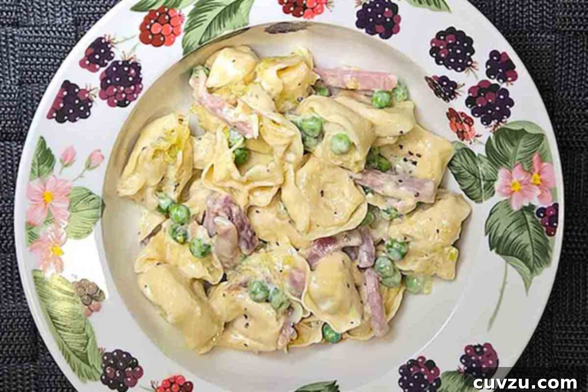 Creamy One-Pan Prosciutto Pea Tortellini 16 A plate filled with luscious tortellini in a creamy sauce, generously mixed with vibrant green peas and savory prosciutto slices.