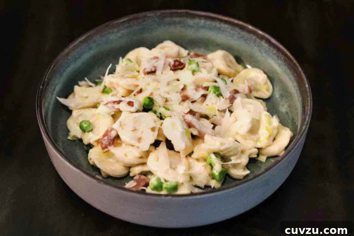Creamy One-Pan Prosciutto Pea Tortellini 17 A beautifully presented bowl of tortellini with prosciutto and peas, generously coated in a luscious cream sauce.