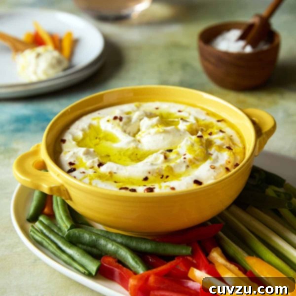 Creamy Whipped Feta 10 A bowl of whipped feta dip topped with oil and lemon zest on a platter of raw vegetables.