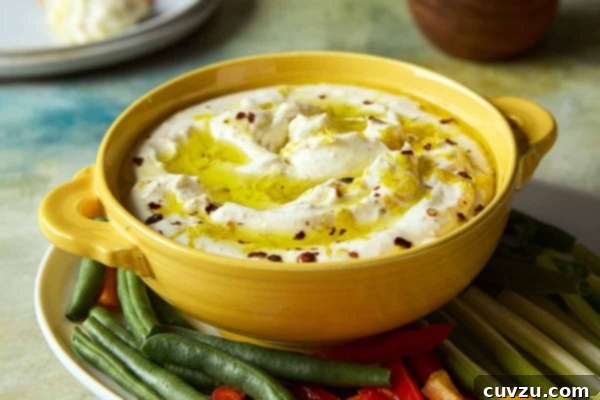 Creamy Whipped Feta 14 A bowl of whipped feta dip topped with oil and lemon zest on a platter of raw vegetables.