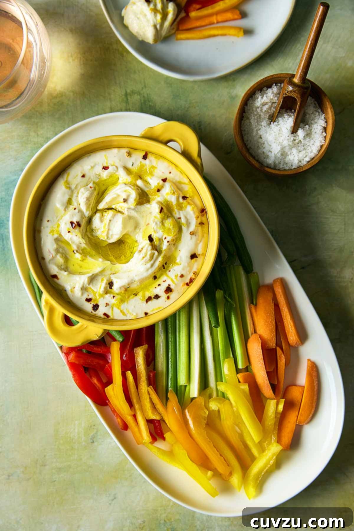 Creamy Whipped Feta 9 A bowl of whipped feta dip topped with oil and lemon zest on a platter of raw vegetables.