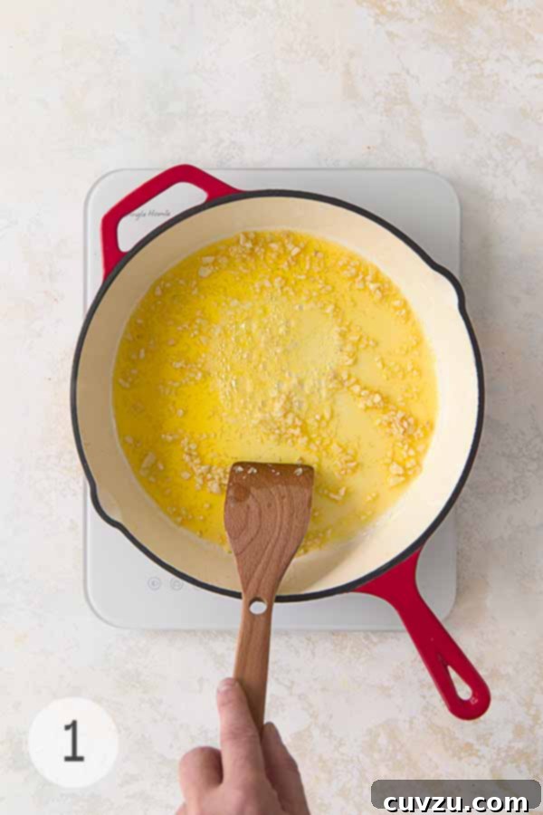 Garlic Lemon Shrimp Scampi 6 Garlic cooking in melted butter and olive oil in a red-handled skillet over medium-low heat, stirred with a wooden spatula.