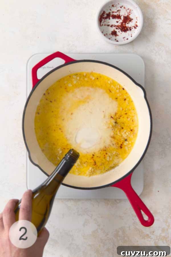 Garlic Lemon Shrimp Scampi 7 White wine being poured into a skillet of garlic butter, with red pepper flakes nearby, creating the flavorful base for shrimp scampi.