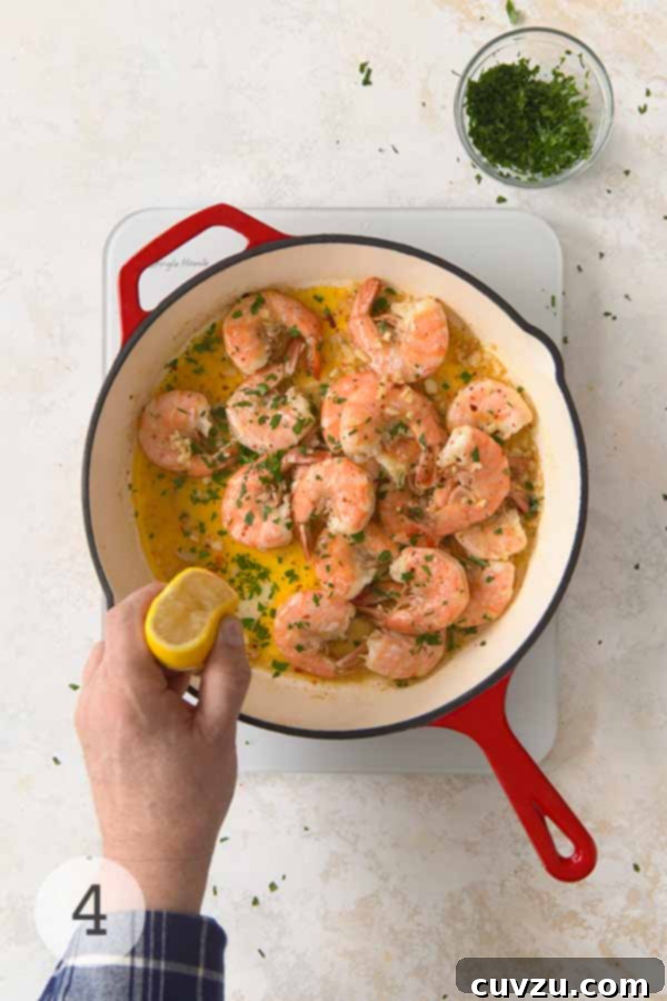 Garlic Lemon Shrimp Scampi 9 A hand squeezing fresh lemon juice over cooked shrimp scampi in a skillet, garnished with chopped parsley.